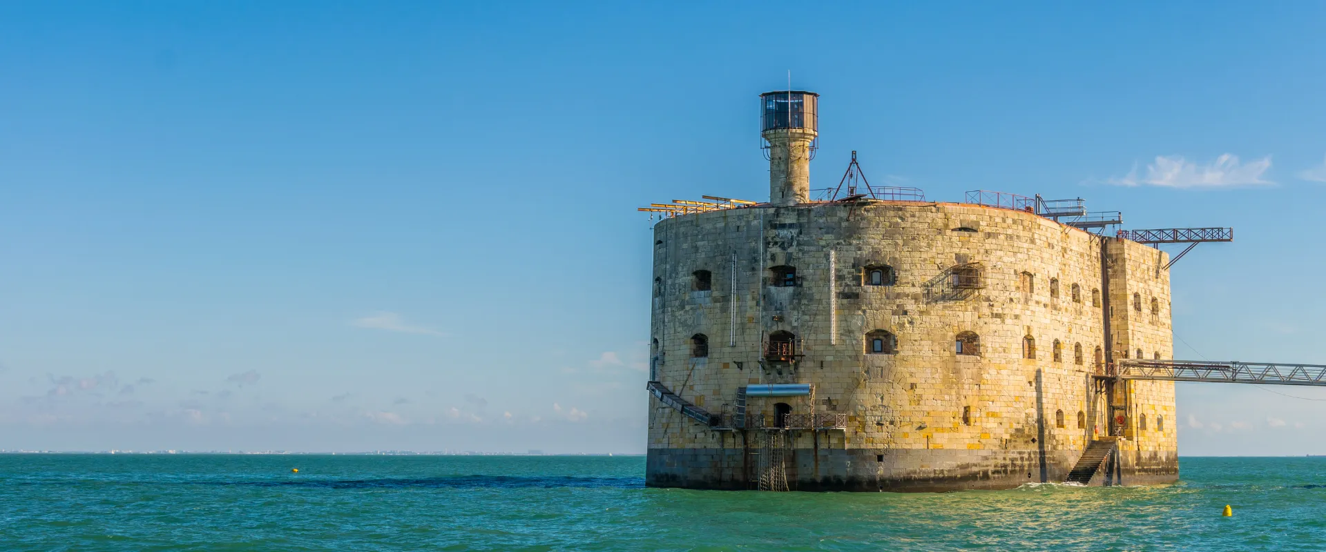 Fort médiéval en pierre dans la mer turquoise sous ciel bleu.