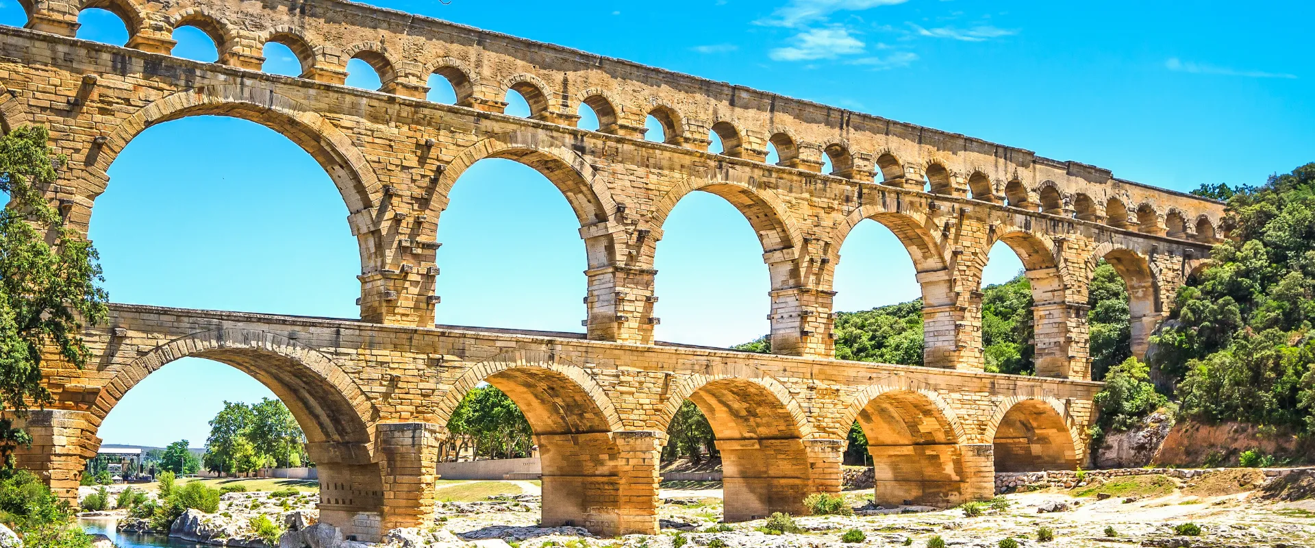 Pont du Gard, aqueduc romain en pierre avec arches superposées et rivière en dessous.