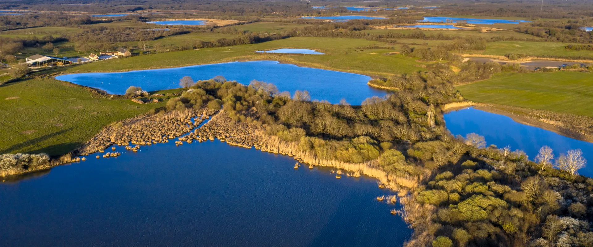 Lacs bleus entourés de forêts et prairies vertes en Indre, vue aérienne panoramique.