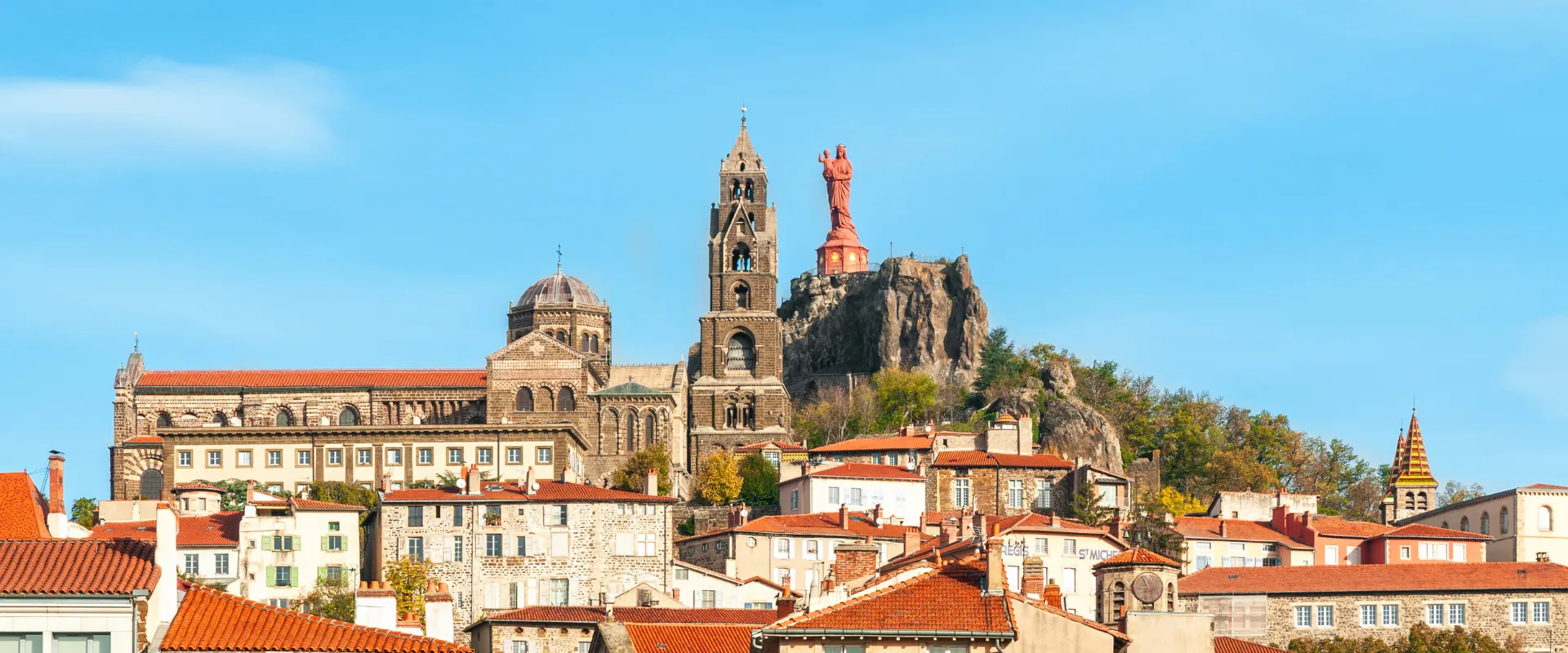 Cathédrale du Puy-en-Velay avec rocher volcanique et statue rouge dominant la ville.