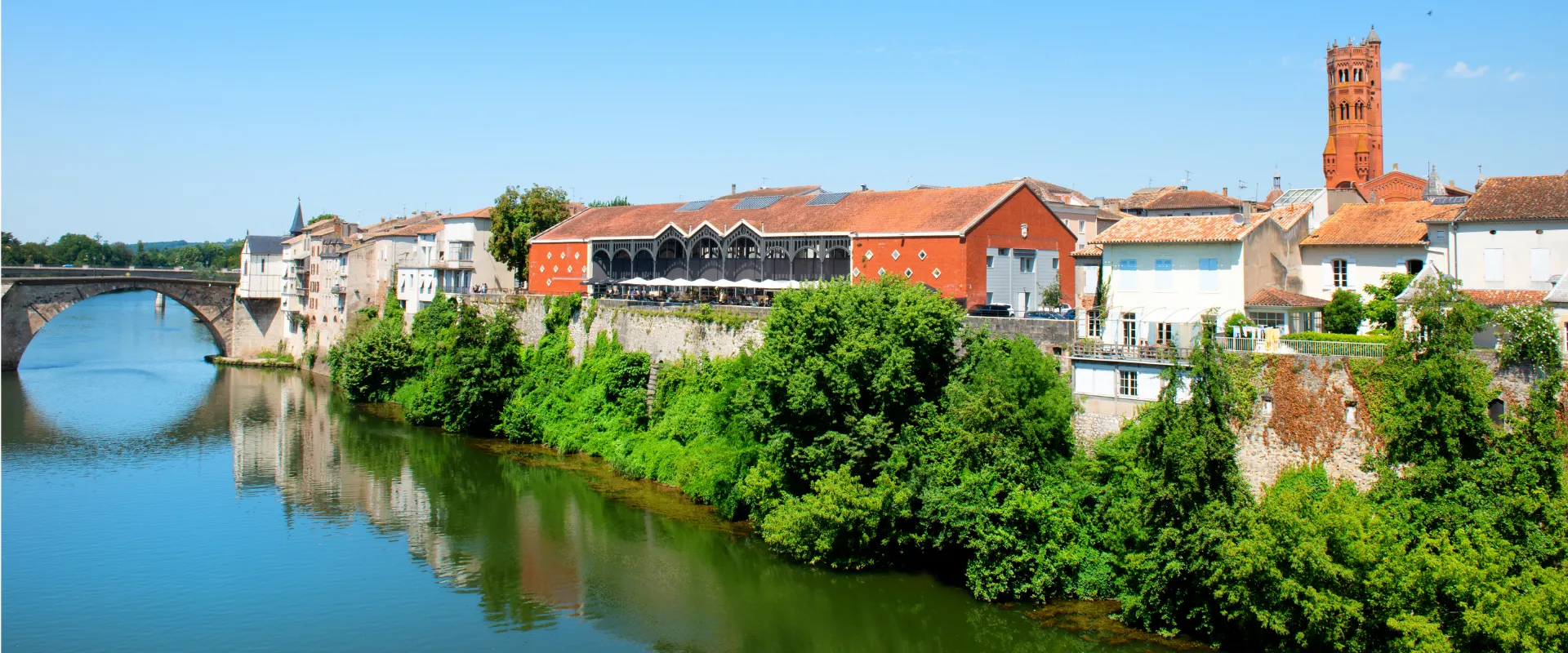 Cahors médiévale avec pont gothique, tour rouge et maisons anciennes sur la rivière Lot.