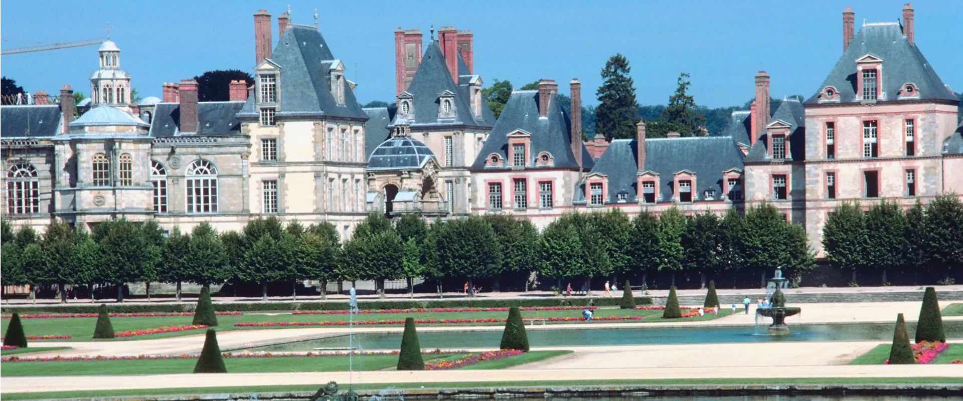 Château de Fontainebleau avec jardins à la française, topiaires et bassin ornemental.