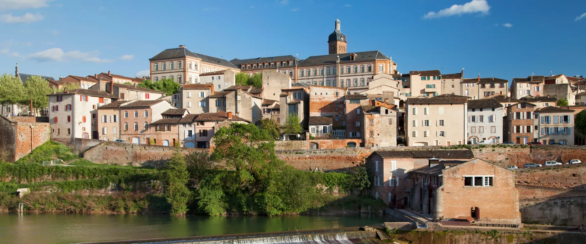 Village médiéval français au bord d'une rivière avec église et maisons colorées historiques