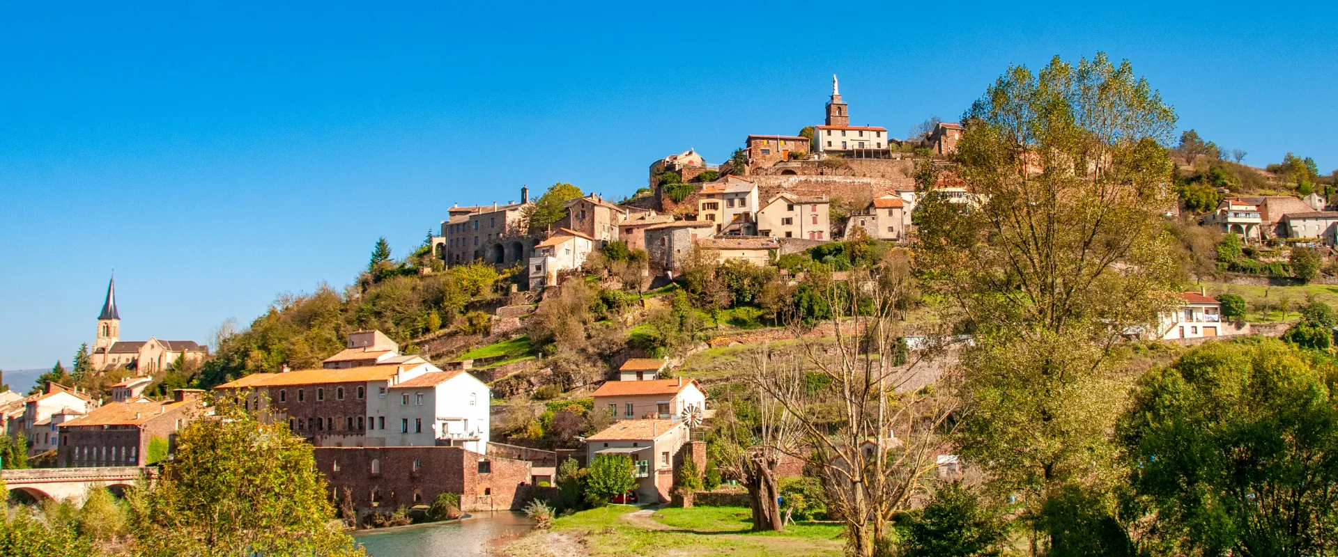 Village médiéval perché sur colline avec église et rivière en Tarn-et-Garonne