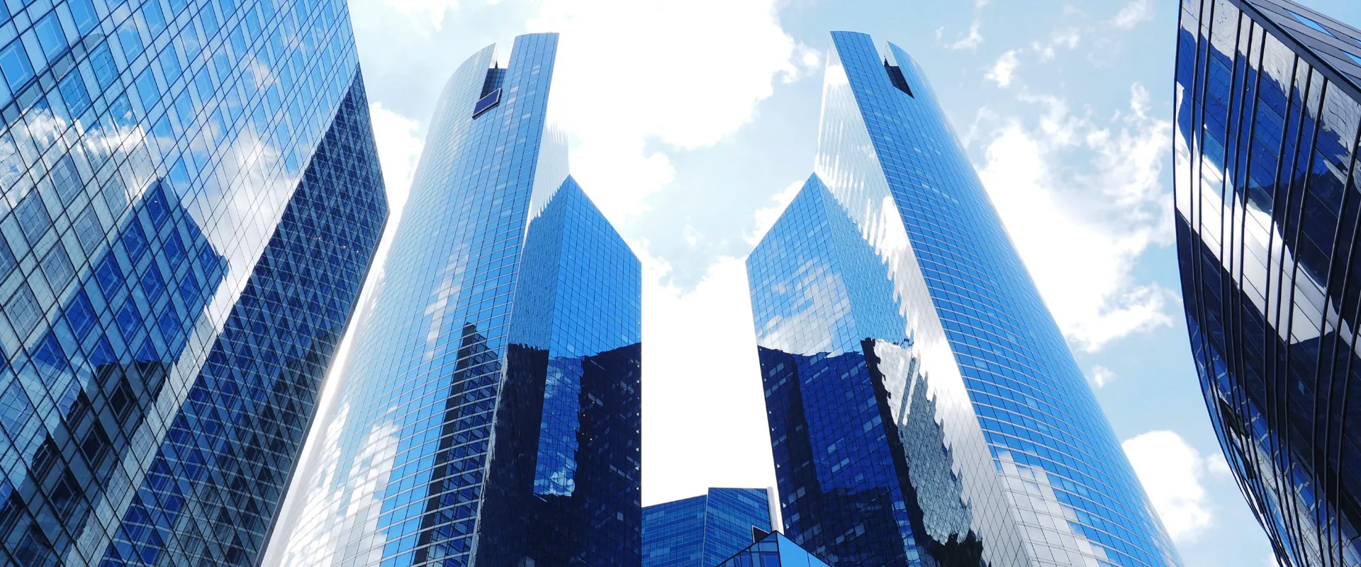 Immeubles de bureaux modernes en verre bleu reflétant le ciel nuageux à La Défense.